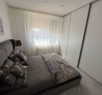 Ein Schlafzimmer in einem Einfamilienhaus mit dunkler Bettwäsche und einem großen Schrank.