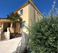 Ein Einfamilienhaus in Komárno mit Terrasse, Gartenstuhl und Palmenbaum im Hof.