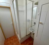 Badezimmer mit Dusche und weißen Fliesen in einer Einzimmerwohnung.