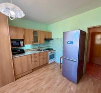 Küchenzeile mit Mikrowelle und Kühlschrank in einer Einzimmerwohnung, Boden mit Holzdekor.