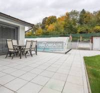 Die Terrasse des Einfamilienhauses in Domaniža mit Gartenmöbeln und einem überdachten Pool.