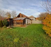Ein Einfamilienhaus in Dlhá Ves mit Garten, Holzanbauten und herbstlicher Vegetation.