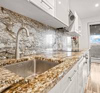 Küche mit Arbeitsplatte aus Stein und Bodenbelag in Holzoptik in einer 3-Zimmer-Wohnung.