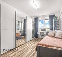 Ein Zimmer mit einem Spiegelschrank, einem Schreibtisch und einem Boden mit Holzdekor in einer 3-Zimmer-Wohnung.