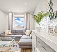 Wohnzimmer mit grauem Sofa, Glastisch und Holzboden.