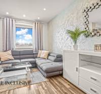 Wohnzimmer in einer 3-Zimmer-Wohnung mit einem bequemen Sofa und einem Boden in Holzoptik.