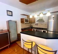 Küche in einer 3-Zimmer-Wohnung mit Bartresen, Metallstühlen und eleganten Lampen.