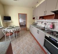 Küche in einer 3-Zimmer-Wohnung mit einer Eckküche, einem Tisch und einem Fernseher an der Wand.