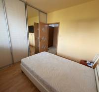 Schlafzimmer in einer 3-Zimmer-Wohnung mit Bett, Kleiderschränken und Boden in Holzdekor.