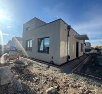 Ein Einfamilienhaus im Bau in Hubice ohne Geländeanpassung. Klarer Himmel und Sonnenlicht.