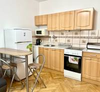 Küche in einem Einzimmerapartment mit Holzboden, Geräten und Sitzgelegenheiten.