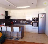 Küche in einer 3-Zimmer-Wohnung mit Bartresen, weißen Schränken und modernen Geräten.