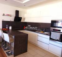 Eine Küche mit weißen Schränken und einer Bartheke in einer 3-Zimmer-Wohnung.