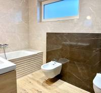 Badezimmer in einem Einfamilienhaus mit Badewanne, Waschbecken, Bidet und Boden mit Holzdekor.