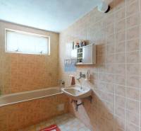 Badezimmer in einem Einfamilienhaus mit älteren Fliesen, Badewanne und Waschbecken.