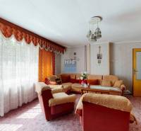 Wohnzimmer in einem Einfamilienhaus mit Blumenmuster-Tapete, weichem Sofa und langen Vorhängen.