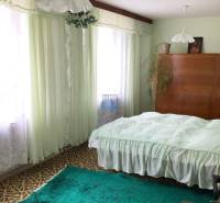 Schlafzimmer im Einfamilienhaus mit Teppichen, Vorhängen und einem Holzschrank.