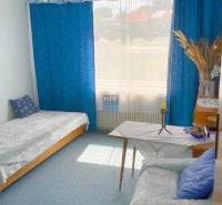 Ein Zimmer in einem Einfamilienhaus mit blauen Vorhängen, einem Sofa und einem Bett.