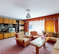 Wohnzimmer in einem Einfamilienhaus mit Sitzgarnitur, Wohnwand und Blumen.