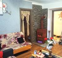 Wohnzimmer in einer 2-Zimmer-Wohnung mit Kachelofen und Boden in Holzoptik.