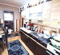 Küche in einer 2-Zimmer-Wohnung mit Holzboden und geometrischen Tapeten.