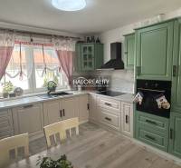 Küche in einem Einfamilienhaus mit Holzmöbeln und Vorhängen.