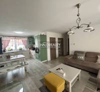 Obývačka v rodinnom dome so sedacou súpravou, stolom a kuchynskou linkou.