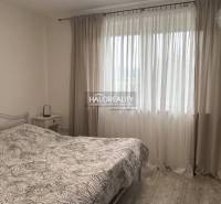 Schlafzimmer mit Bett und Vorhängen in einem Einfamilienhaus, helle Atmosphäre.