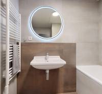 Badezimmer mit Waschbecken, Spiegel und Badewanne in einer 2-Zimmer-Wohnung, dezente Fliesen.