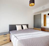 Schlafzimmer mit großem Bett, Spiegelschrank und Holzboden in einer Zweizimmerwohnung.