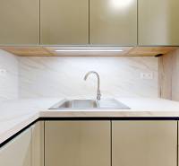 Küchenzeile mit Spüle, hellen Schränken und Rückwand in einer Zweizimmerwohnung.