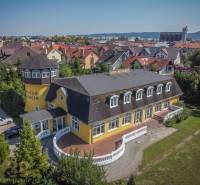 Gelbes Hotel mit Turm, umgeben von einem Garten in der Stadt Poprad, Hotels und Pensionen.