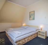 Ein Zimmer mit einem Doppelbett, einem Nachttisch, einem Bild, einer Lampe, Teppichen in Hotels und Pensionen.