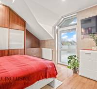 Schlafzimmer im Einfamilienhaus mit Bett, Schrank und Boden in Holzoptik.