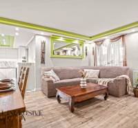 Wohnzimmer in einem Einfamilienhaus mit Holzboden und grünen Details an der Decke.