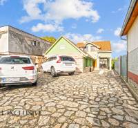 Ein Einfamilienhaus in der Kúpeľná-Straße in Dunajská Streda mit einem gepflasterten Hof und geparkten Autos.