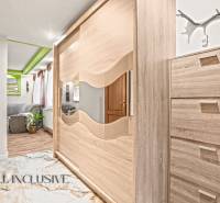 In einem Einfamilienhaus sieht man einen Kleiderschrank mit Spiegel und einen Boden mit Holzdekor.