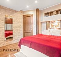 Schlafzimmer im Einfamilienhaus mit Bett, Steindetails und Boden mit Holzdekor.