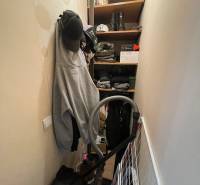 Stauraum mit Kleidung, Hüten, Schuhen und Staubsauger in einer Einzimmerwohnung.