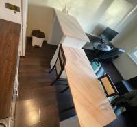 Küche in einer Einzimmerwohnung mit Holzboden, Bartresen und Arbeitstisch.