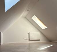 Dachgeschosszimmer mit Holzboden und Dachfenstern in einer 3-Zimmer-Wohnung.