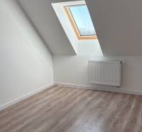 Dachgeschosszimmer mit Holzboden und Dachfenster in einer 3-Zimmer-Wohnung.