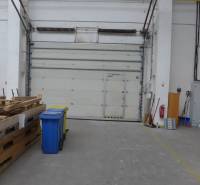 Lagerhäuser und Hallen mit Paletten, Containern und großen Türen.