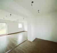 Innenraum eines Einfamilienhauses mit Holzboden und großen Fenstern zum Garten.