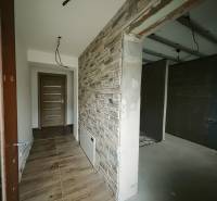 Ein Flur mit einer Wand in Steinoptik und einem Boden in Holzoptik in einem Einfamilienhaus.