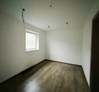 Ein Zimmer in einem Einfamilienhaus mit weißen Wänden und einem Boden in Holzoptik.