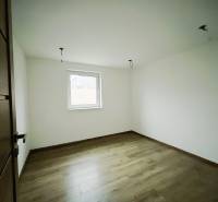 Ein Zimmer in einem Einfamilienhaus mit weißen Wänden und einem Boden in Holzoptik.