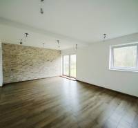 Ein geräumiges Wohnzimmer mit einer Wand aus Steinzeug und einem Boden in Holzoptik in einem Einfamilienhaus.