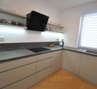 Eine Küche in einem Einfamilienhaus mit einer dunklen Arbeitsplatte und einem Boden in Holzoptik.