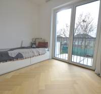 Ein Zimmer in einem Einfamilienhaus mit einem Bett, einem großen Fenster und einem Boden mit Holzdekor.